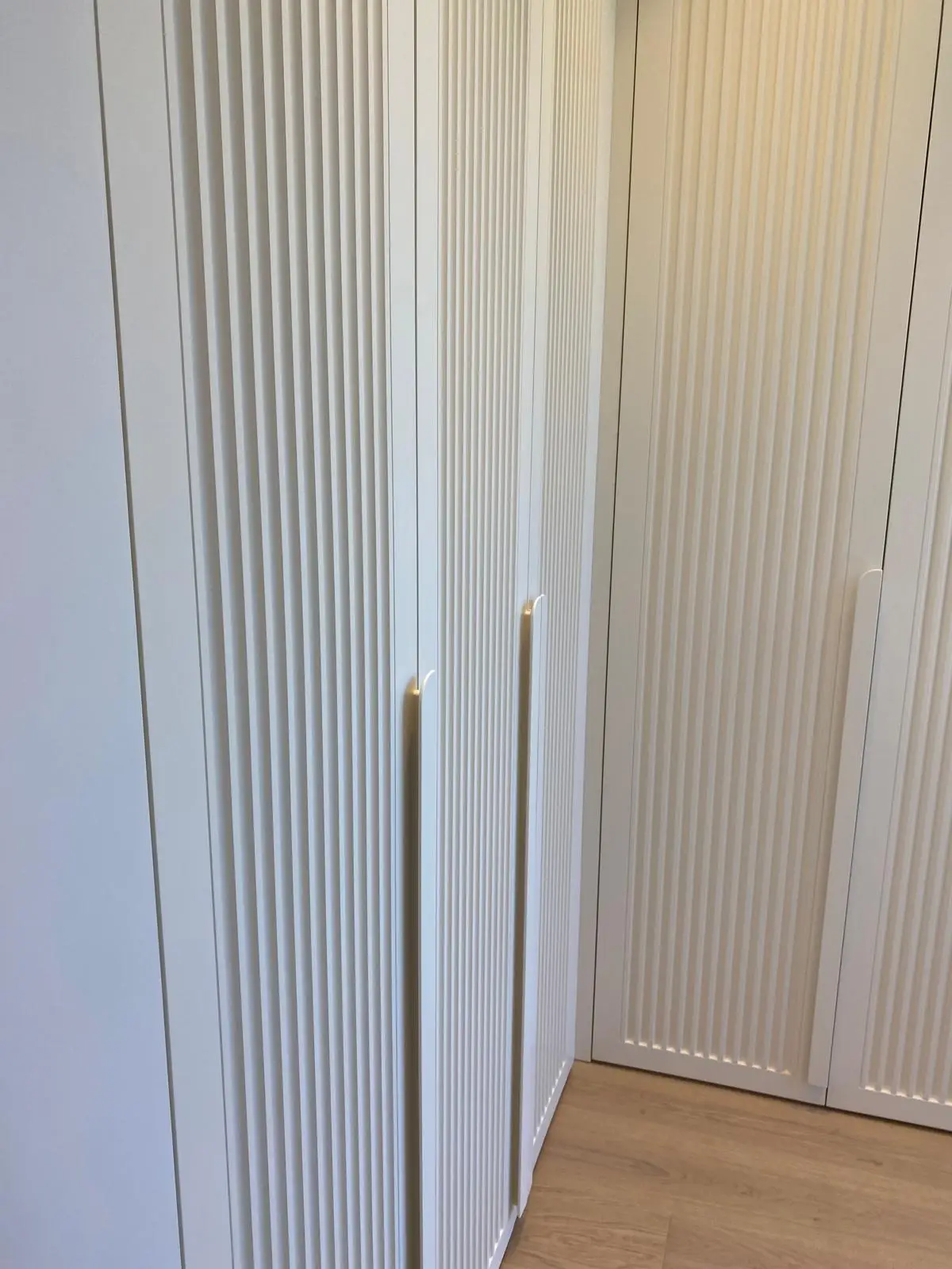 Fluted wardrobe doors in white lacquer with slimline handles