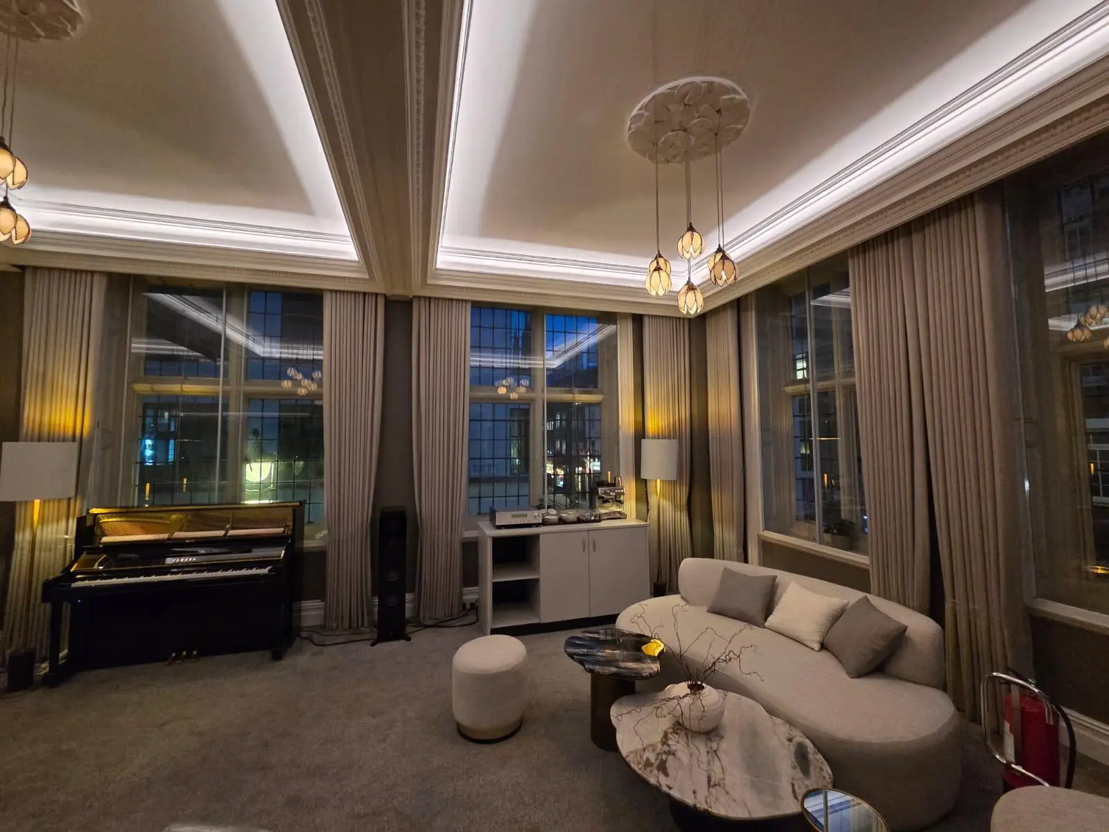 Curved upholstered sofa with stone-topped coffee and side tables, and an upholstered ottoman